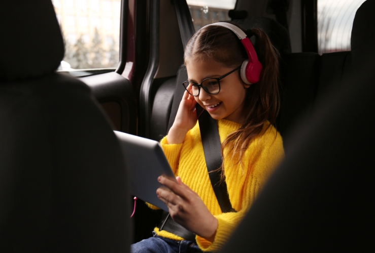 Young girl watching film on table in car on long drive