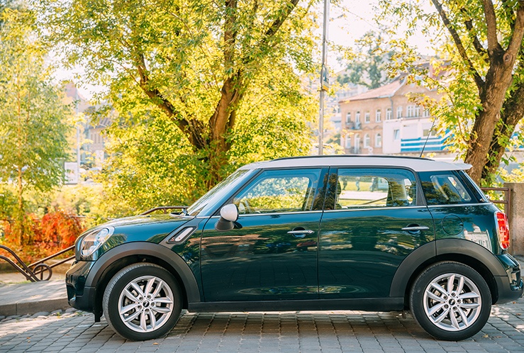 Green car parked in front of trees