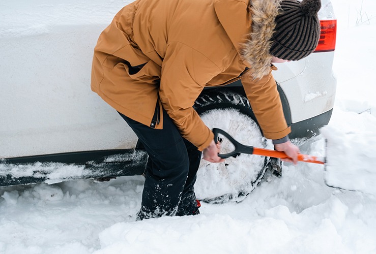 Man digging out a stuck car in the snow