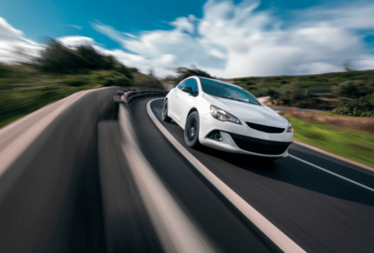 White car cornering mountain road, with speed blur