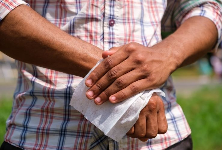 Man cleaning hands with wet wipes