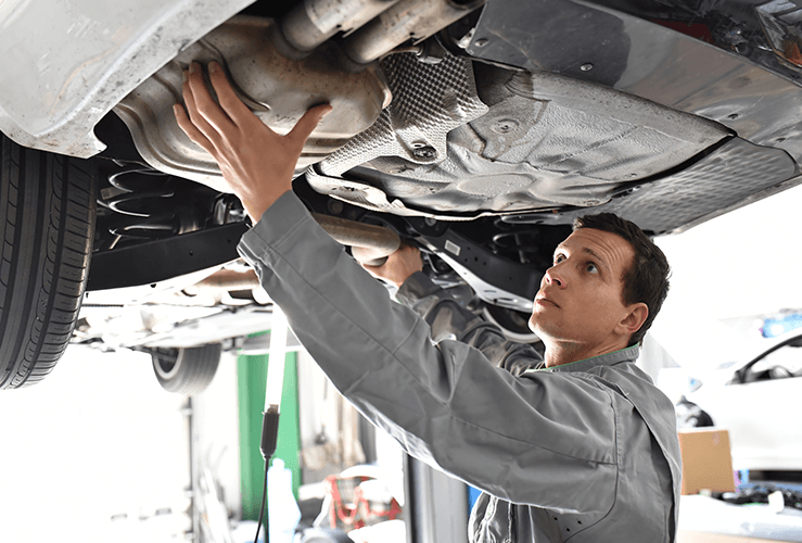 Mechanic looking under raised car 