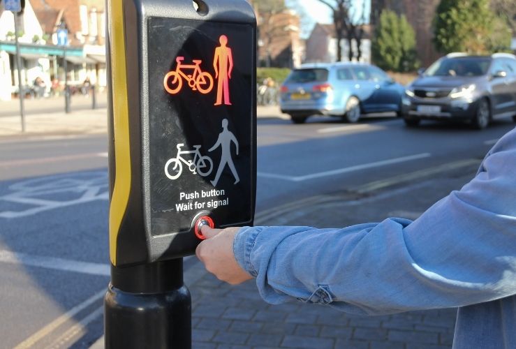 Pedestrian pressing button waiting to cross road