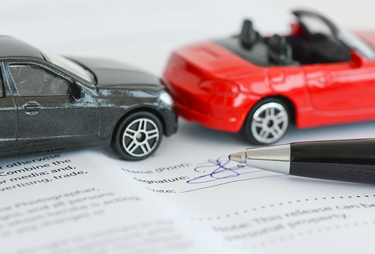 Car insurance agreement next to 2 toy cars crashing